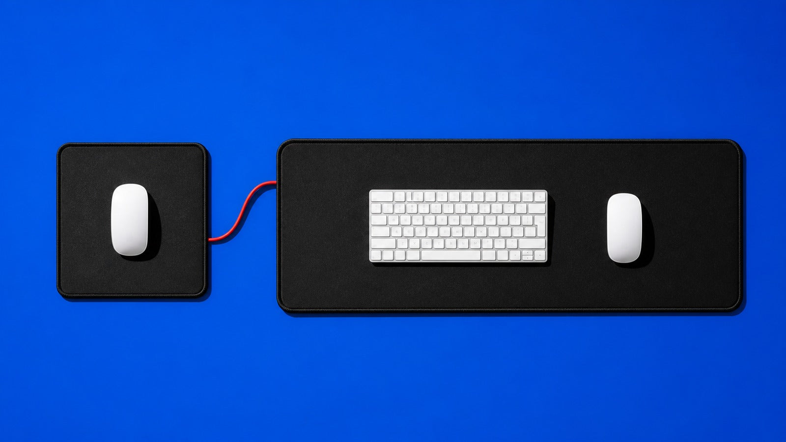 Regular mouse pad and extended keyboard mat compared from above on a royal-blue background
