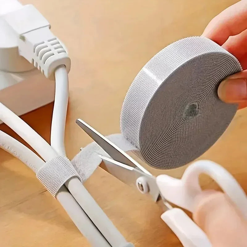 Cutting the reusable cable wrap to length with scissors around white cables