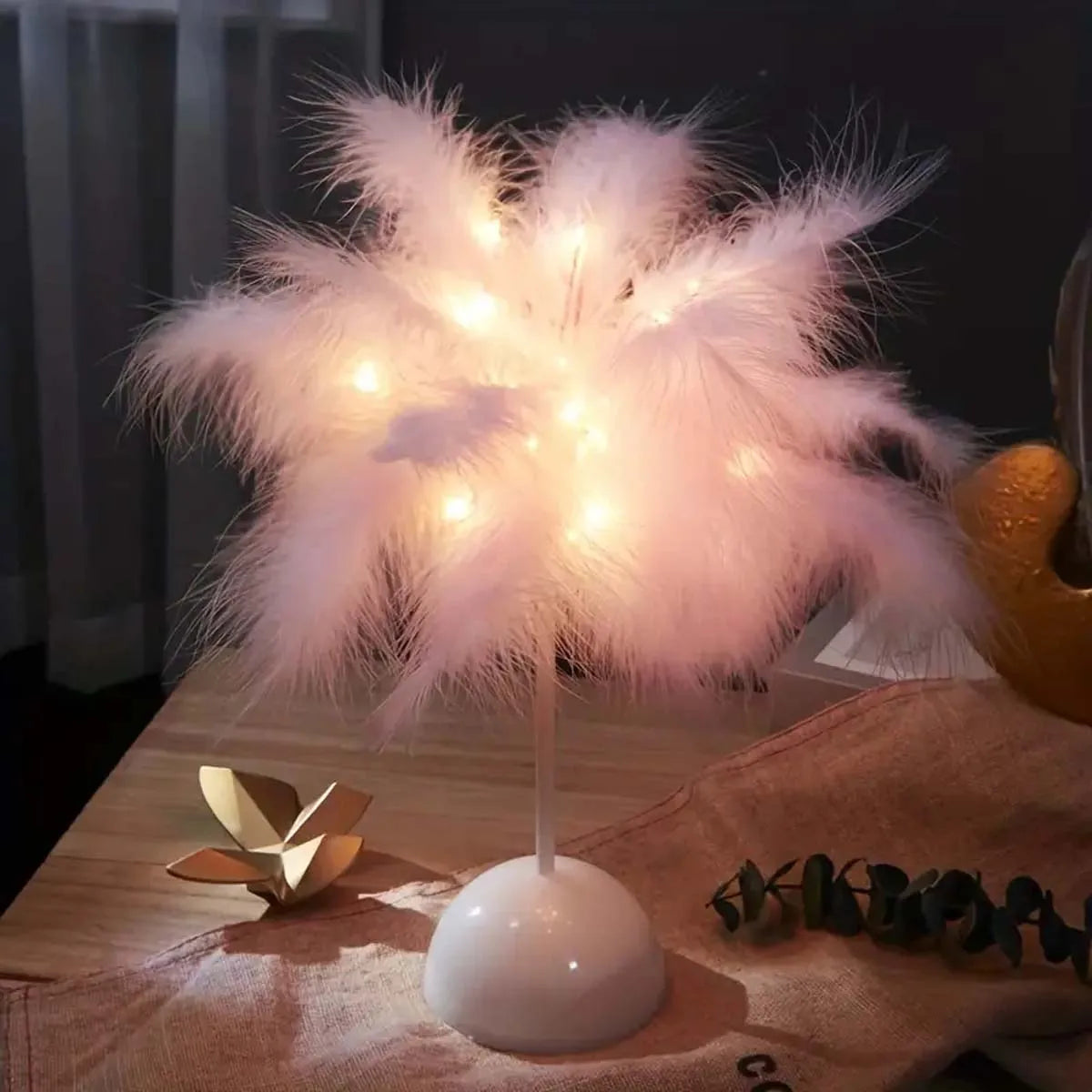 Pink feather LED table lamp glowing on a bedside table